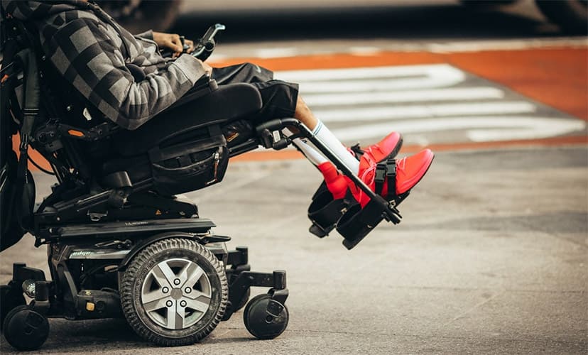 A person on a power wheelchair with elevated footrests
