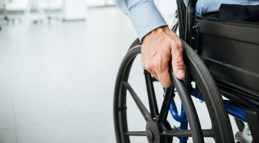 A man's hand propelling a wheelchair's wheel