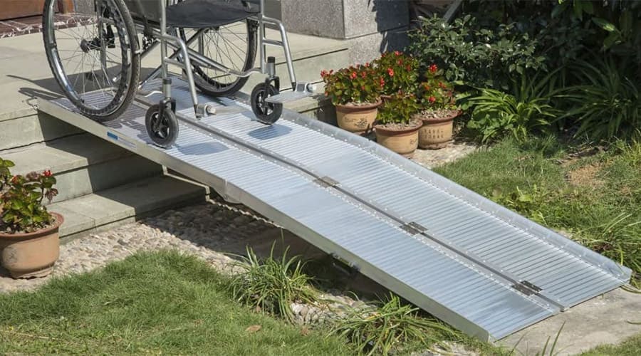 Portable access ramp installed on a three-step chair with a wheelchair on the top part
