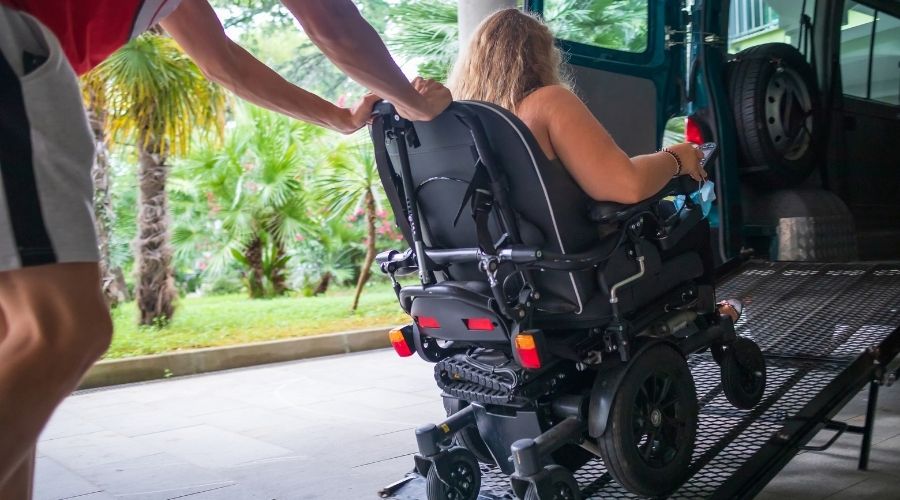 A woman in a wheelchair being pushed through a ramp into a used van 