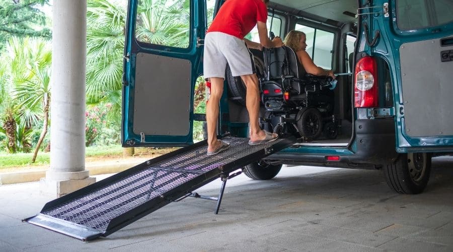 A man pushing a wheelchair with a woman in it into a used disability van