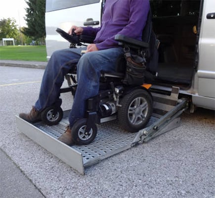 A man in an off road wheelchair on a ramp attached to a van