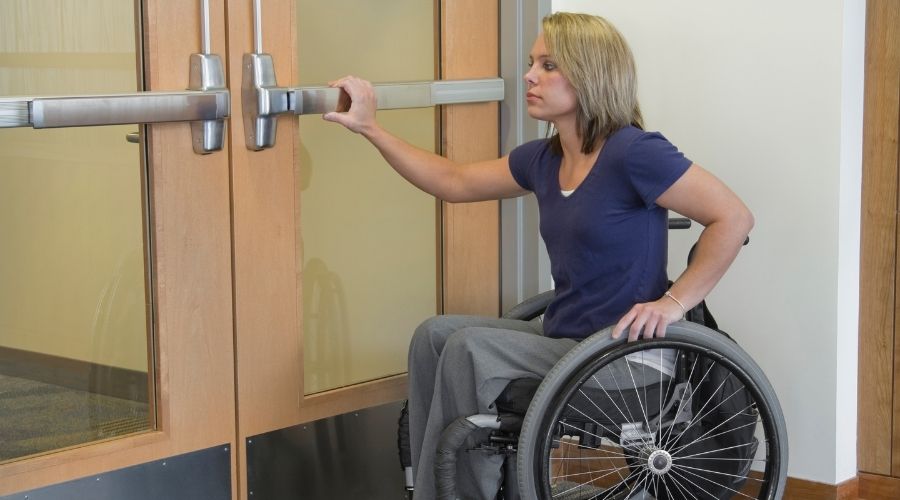 A woman reaching a wheelchair accessible door