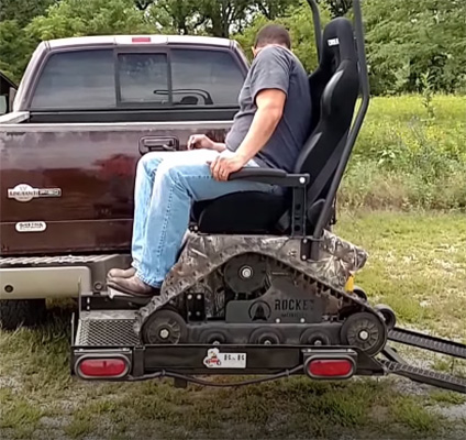 A man on a Rocket Mobility Tomahawk All-Terrain Wheelchair mounted on a wheelchair lift at the back of a pick-up truck