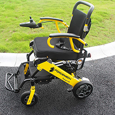 Forcemech Voyager R2 folding power wheelchair on a concrete road and grassy space to the side